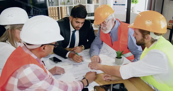 Male and Female Team of Engineers with Bearded Head Engineer Holding a Meeting About Future Building alt