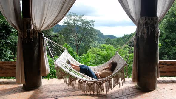 A woman lying and relaxing on hammock while looking at green nature