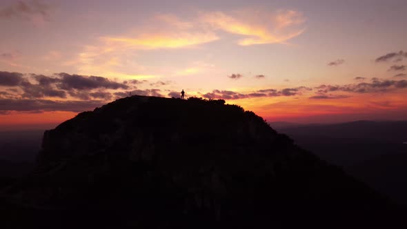 Silhouette of a Person on Top of a Mountain at Sunset  Aerial Drone View