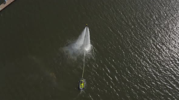 A Man Flies Over the River on a Flyboard and Dives Into the Water alt