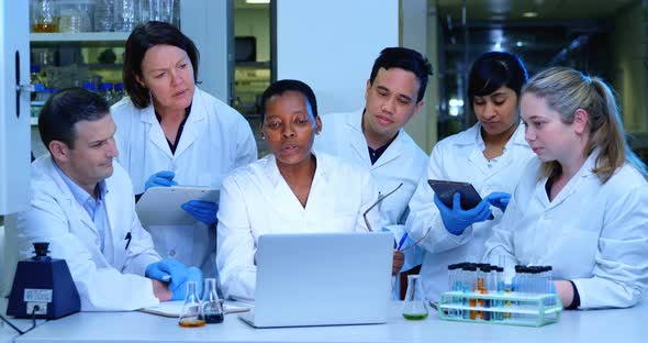 Team of scientist discussing over a laptop 4k alt