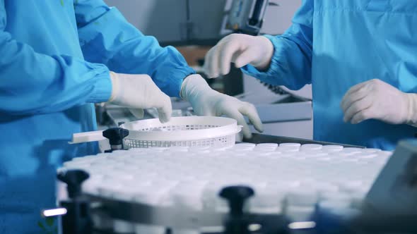 Pharmacologists are Sealing Plastic Tubs with Pills alt