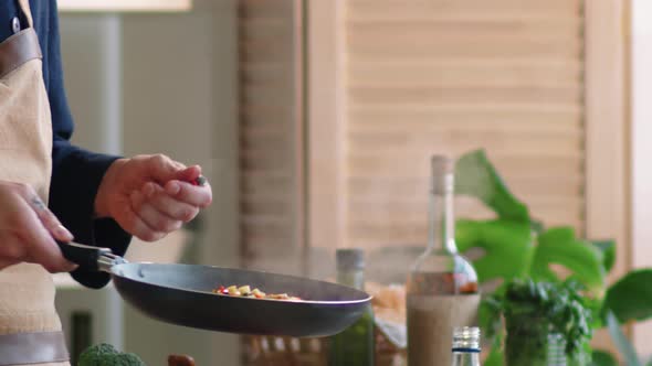Male Chef Tossing Chopped Vegetables in Skillet alt