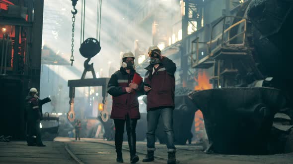 Steel Mill Colleagues in Safety Wear are Walking Along the Factory alt