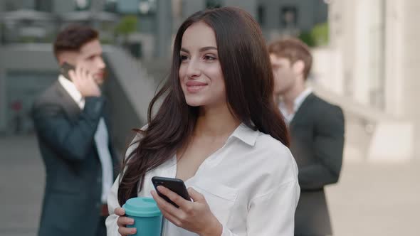 Smiling Business Woman Using Smartphone on Street of Business Center Downtown.. Attractive Young alt