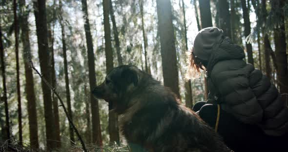 A Girl and a Dog Sitting in the Forest Looking Around
