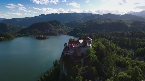Stately Bled castle on precipice above city of Bled, Slovenia; drone view alt