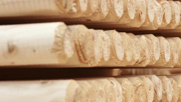 Piles of Wooden Logs in Storage Shelves. Round Wooden Sticks in Warehouse alt