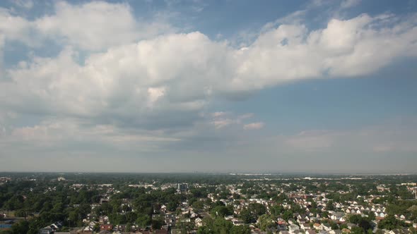 An aerial time lapse over a quiet suburban neighborhood on a sunny day with blue skies with white cl alt