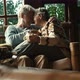 Happy old senior couple kiss and enjoy love and relationship together sitting on a sofa in home - VideoHive Item for Sale
