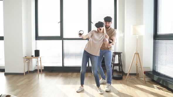 Positive Beautiful Caucasian Couple Playing Video Games in Virtual Reality Glasses