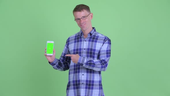 Portrait of Happy Hipster Man Showing Phone and Giving Thumbs Up alt
