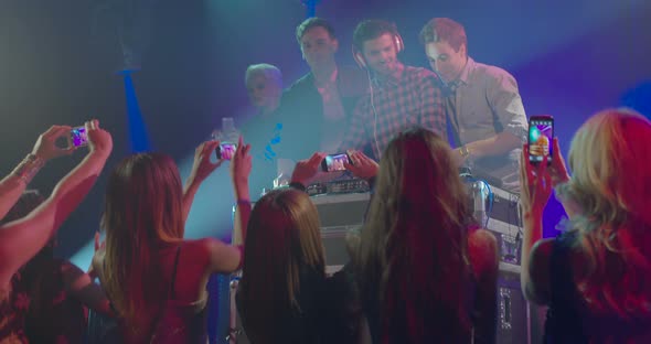 Friends taking photo with mobile phone while enjoying music in nightclub