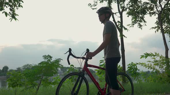 Asian young active male riding bicycle for health in the evening in public park. alt