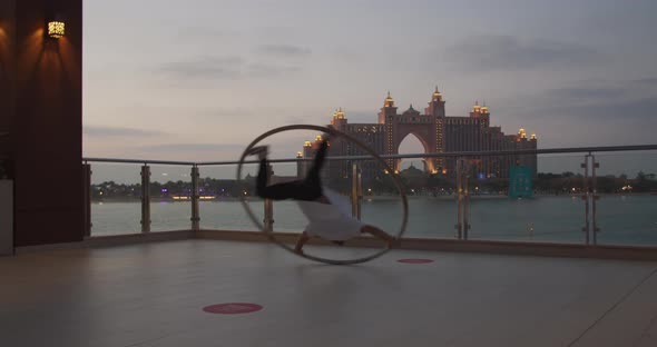 Professional Wheel Gymnast is Spinning in a Wheel with Amazing View Behind alt