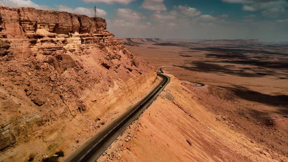 Car Driving on Asphalt Road Through the Desert Sands of the Blue Sky White Clouds