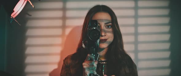 A woman with a vintage camera slowly turning to the left side alt