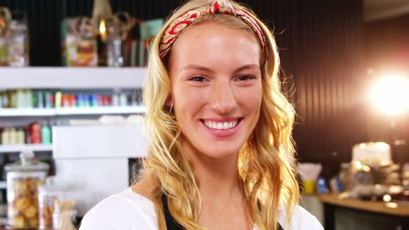 Portrait of smiling waitress standing with arms crossed alt
