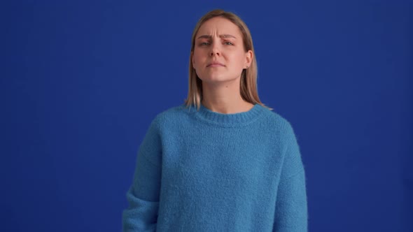 Displeased woman wearing blue sweater showing blah blah gesture alt