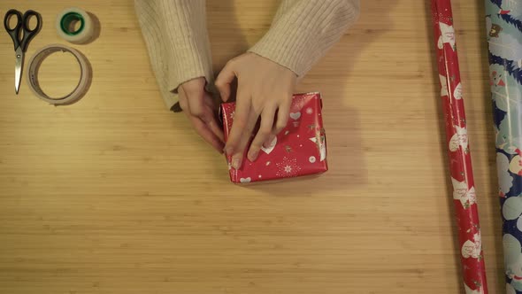 Young Woman Packs Christmas Present in Red Paper