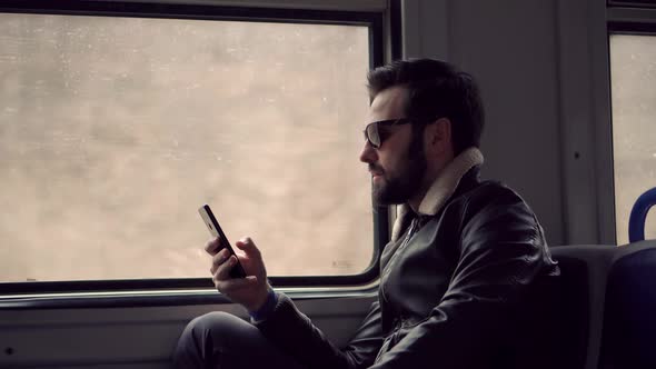 Guy Talking On Cellphone. Man Talking On Smartphone In Train. Man In Sunglasses Using Mobile Phone. alt