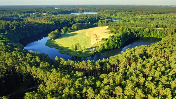 Blue winding river between green forests in Poland alt