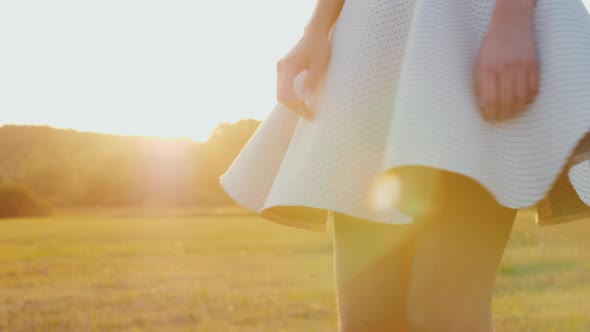 A Young Slim Woman in a Light Skirt Is Spinning in a Meadow alt