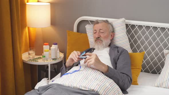 Sick Senior Male Check the Pulse with Pulse Oximeter alt