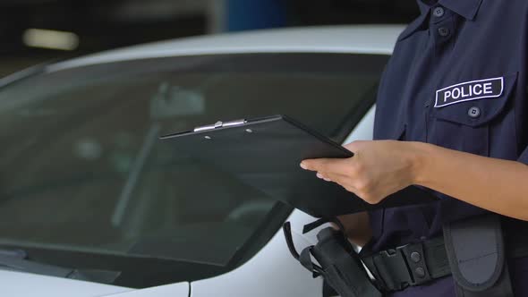 Female Parking Warden Signing Ticket and Attaching It to Car Windshield, Rules alt