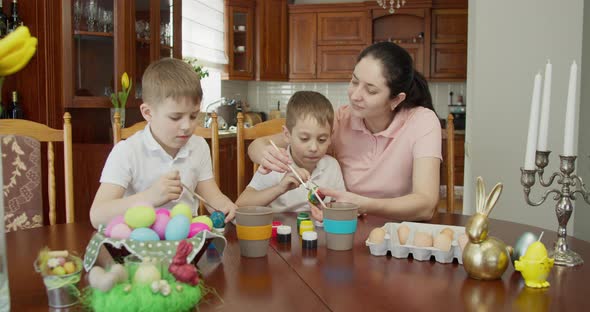 Mom Helps Her Sons Paint Easter Eggs alt
