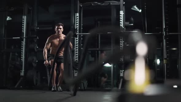 Athletic Man Performs Exercises with Battle Ropes Endurance Training in the Gym  Slow Motion alt