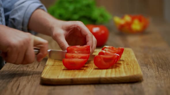 man cuts red tomatoes. cooking process by the chef. salad ingredients. caring man preparing dinner alt