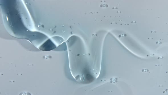 Transparent Blue Cosmetic Gel Fluid with Bubbles Flowing Down on a White Surface alt