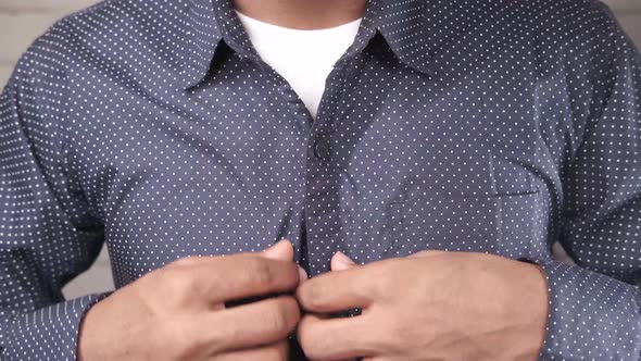 Man Buttoning His Shirt Close Up alt