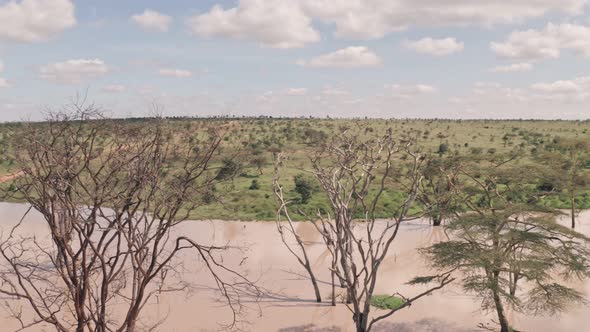 Waterhole lake in Laikipia, Kenya. Aerial spinning drone view of Kenyan landscape alt