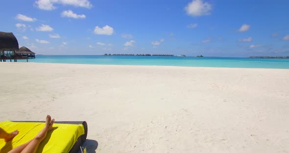 Aerial view of a couple lounging on a beach at a tropical island resort hotel. alt