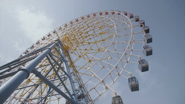 Big Ferris Wheel Rotates at Amusement Park Ride Over Clean Blue Sky alt