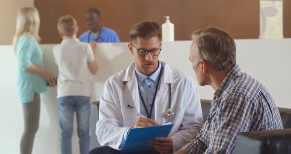 Young Doctor Talking to Mature Patient in Hospital Hallway alt