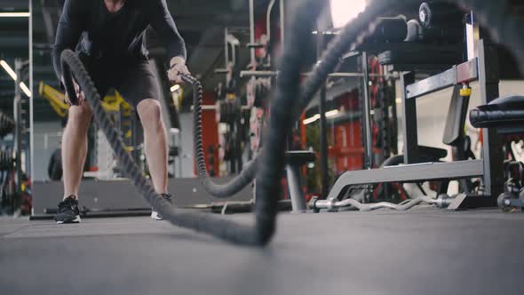 Athletic Man in a Gym Performs Exercises with Battle Ropes Crossfit Endurance Training alt