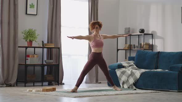 Adult Housewife is Doing Yoga Asanas at Home Training Alone in Living Room Standing on Floor Mat alt