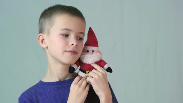 Portrait of a child boy playing with a small Santa Clause toy. alt