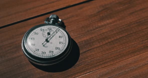 Old Vintage Stopwatch Lies on Wooden Table and Counts the Seconds alt