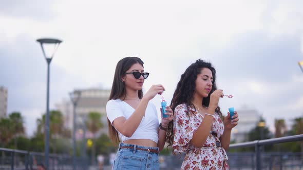 Young Multiethnic Women Having Fun Blowing Soap Bubbles in Town