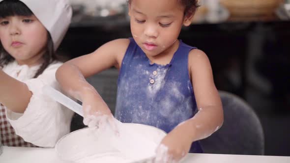 Group of children baking cake together in classroom, Multi-ethnic young boys and girls happy making. alt