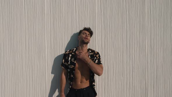 Muscular Man in a Shirt Posing Against a Wall alt
