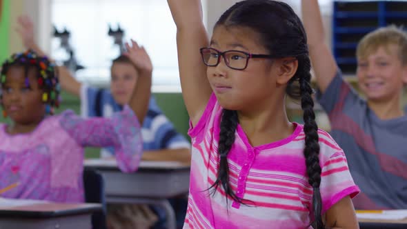 Students in school classroom raise their hands alt