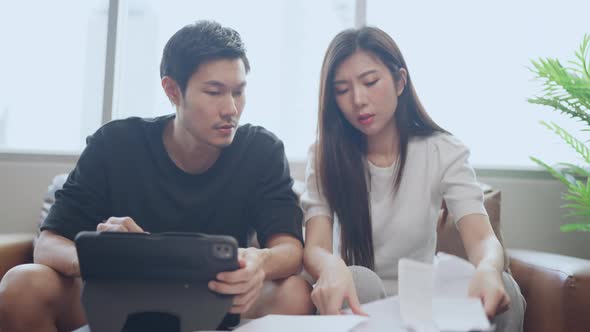 couple checking and calculate financial billing together on sofa involved in financial paperwork alt