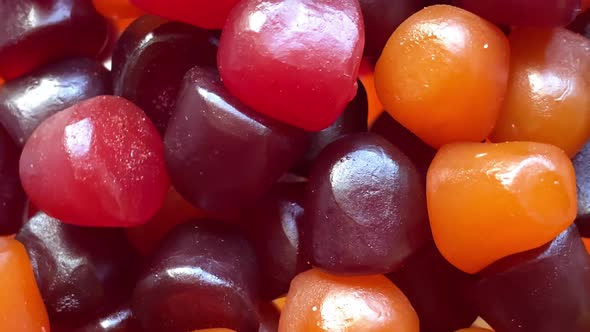 Closeup Texture of Red Orange and Purple Multivitamin Gummies on White Background alt