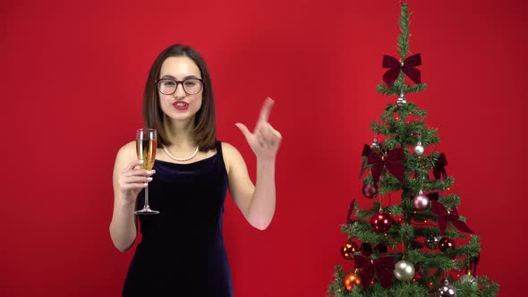 Young Woman Counts Five Seconds To the Holiday with a Glass of Champagne Near the Christmas Tree on alt