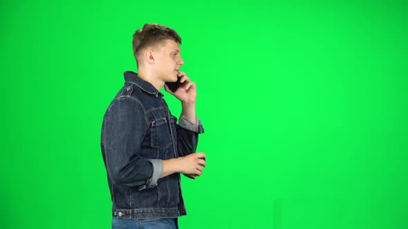 Young Man Walking Talking on the Phone and Drinking Coffee. Chroma Key. Slow Motion. Side View alt
